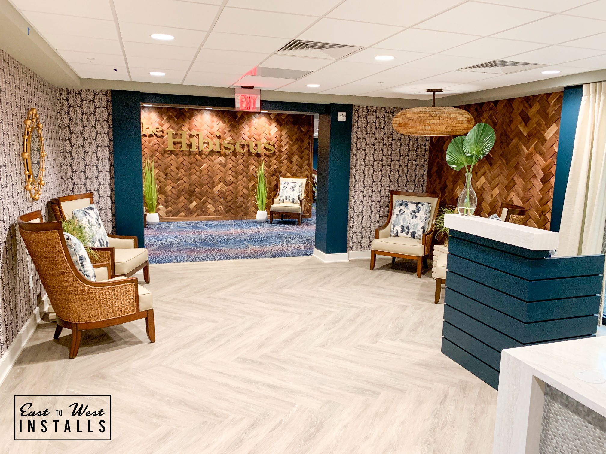 Lobby with Hibiscus feature wall visible — rattan seating, pendant lamp